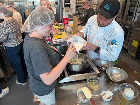 A student from the Class of 2030 works with culinary instructor Russ Barrett to prepare vegetable curry during a culinary medicine event at Kalamazoo Valley Community College on Wednesday, July 22, 2026